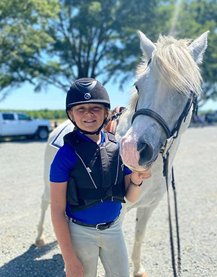 A girl and her pony smiling at the camera.