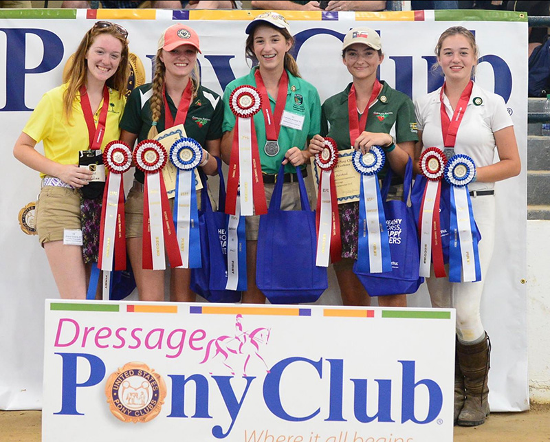 A group of girls all holding awards and smiling at the camera. 