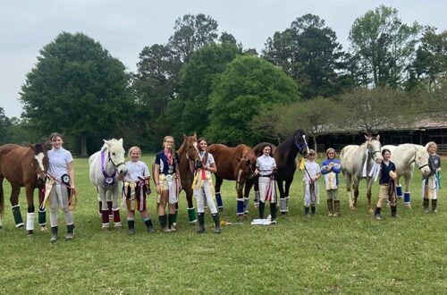 A group of kids and their horses all smiling at the camera.