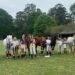 A group of kids and their horses all smiling at the camera.