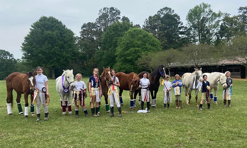 A group of kids and their horses all smiling at the camera.