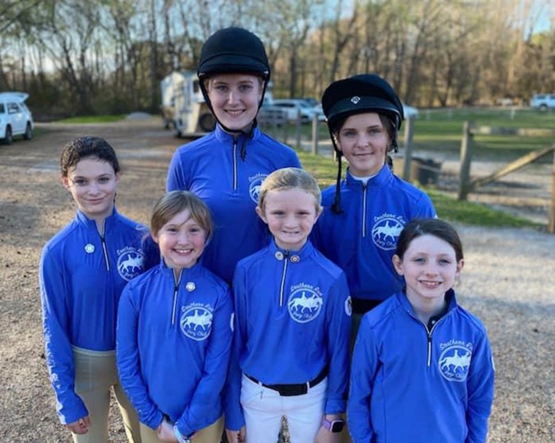 A group of riders smiling at the camera.