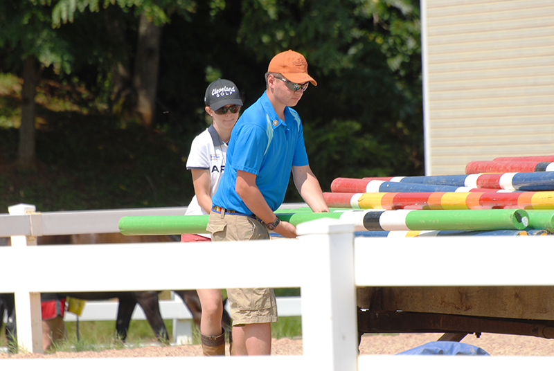 Two people helping to move jumps.