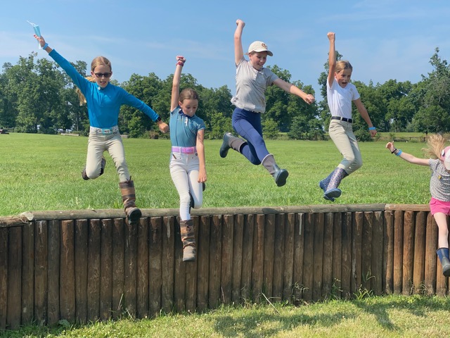 A group of kids jumping off a small wall, smiling.