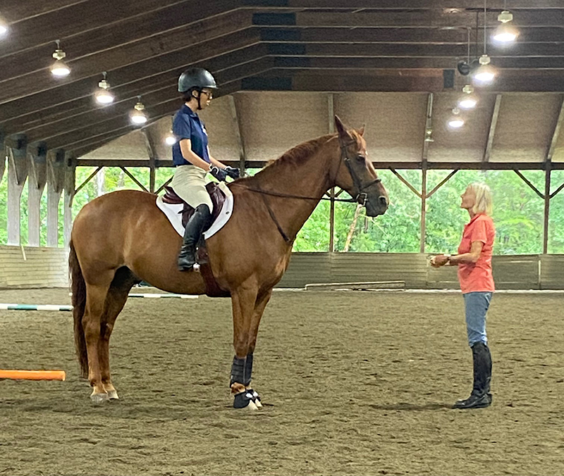 A young girl on her horse talking to an instructor.