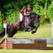 A man jumping his horse outside over a jump on a cross-country course.