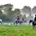 A group of individuals horseback in a hunt field.