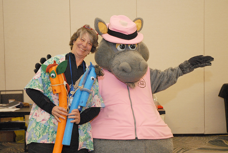 A woman and a horse mascot, smiling at the camera.