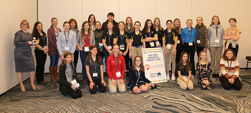 A group of kids sitting in front of the camera, they all participated in the 2023 USPC Research Project Fair.