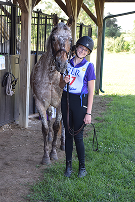 A girl and her horse smiling at the camera.