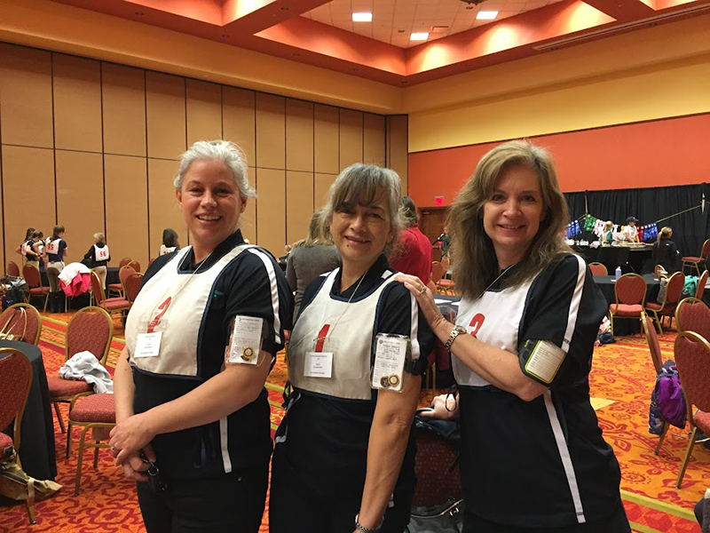 Three adult Pony Club members smiling at the camera.