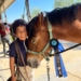 A young boy with his horse, smiling at the camera.