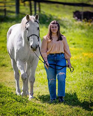 A girl and her horse walking toward the camera.