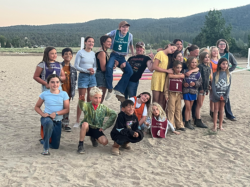 A group of kids posing for the camera, standing in an arena.