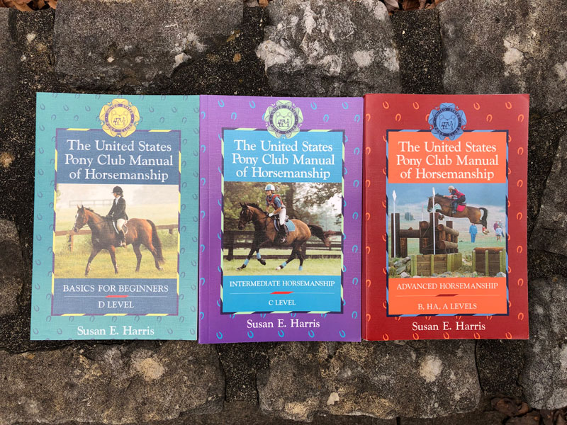 Set of three United States Pony Club Manuals from the 1990s on a stone background