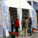 visitors outside the Pony Club trade fair booth in a white tent with Pony Club banners and red geraniums in pots