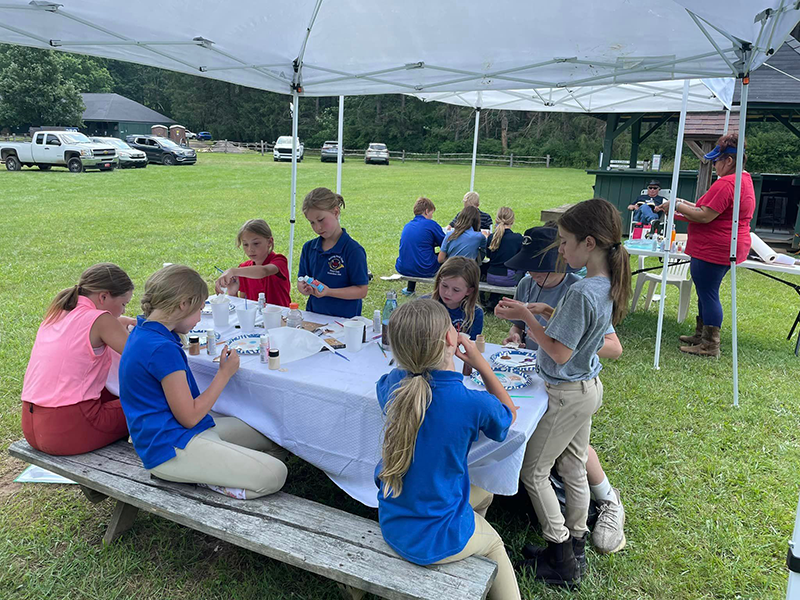 A group of children doing crafts at a picnic table.