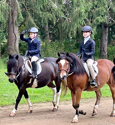 Two young people riding their horses.