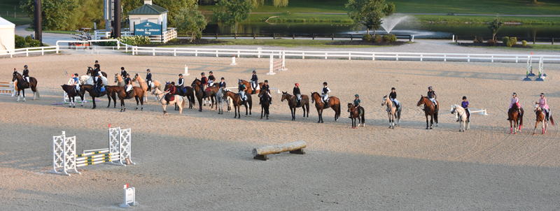 pony club riders lined up on horseback in arena
