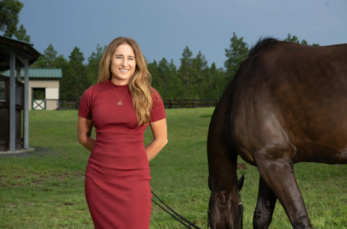 A woman standing outside with her horse.