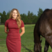 A woman standing outside with her horse.