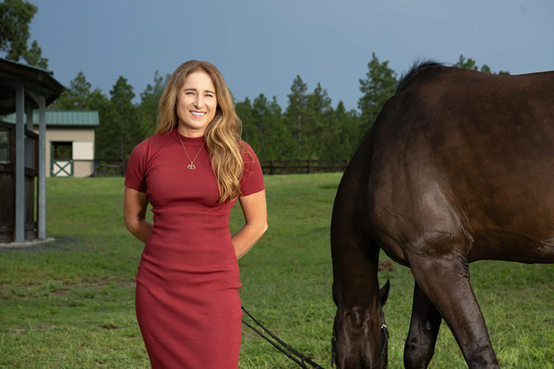 A woman standing outside with her horse.