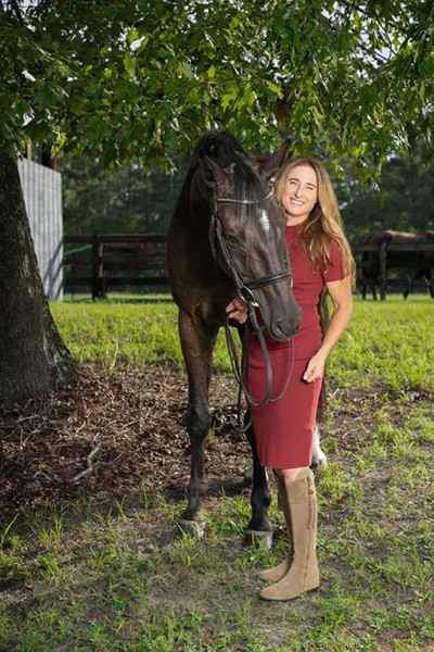 A woman standing outside with her horse.