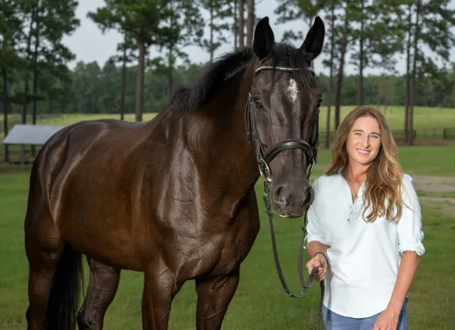 A woman standing outside with her horse.