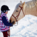 A young girl and her horse out in the snow