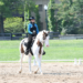 A young girl riding a paint horse in Western Dressage