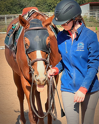 A young girl walkign her horse.
