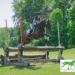 A young woman jumping her horse over a cross-country fence.
