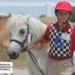 A young man walking his horse, smiling at the camera.