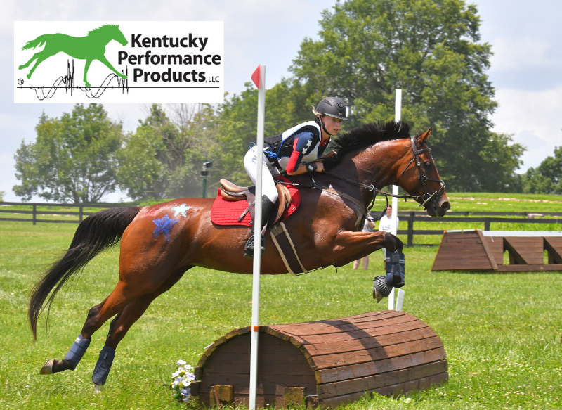A young girl riding her horse over a cross-country jump