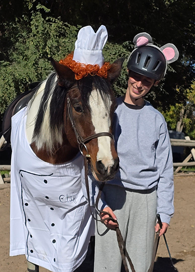 A young woman and her horse dressed up as a mouse and chef.