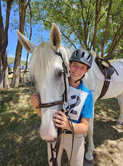A young woman and her horse smiling at the camera.