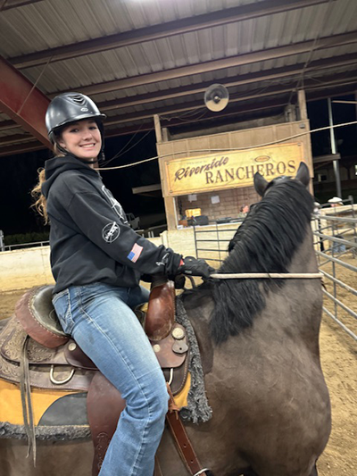A young woman posing while on her horse.