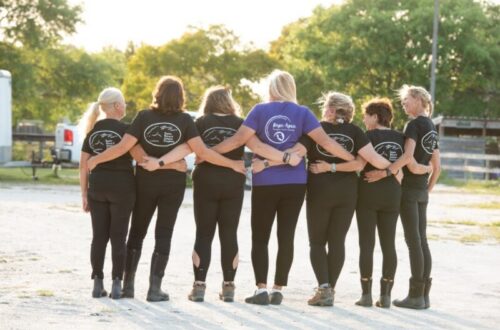 A group of woman standing with their arms linked, their backs to the camera.