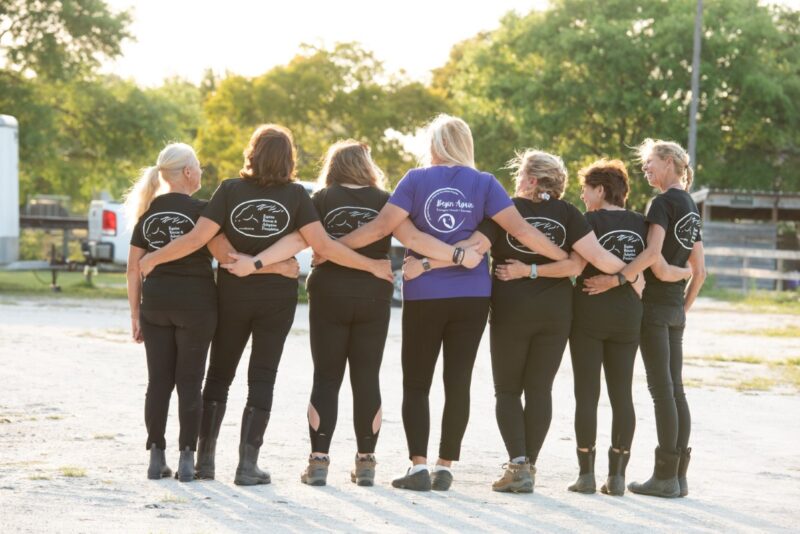 A group of woman standing with their arms linked, their backs to the camera.