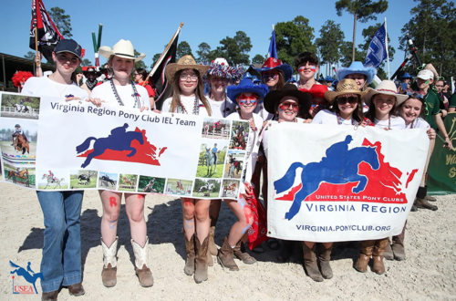 A group of young riders holding banners, smiling for the camera.