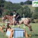 A young adult riding their horse over a cross-country jump