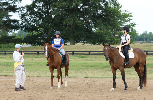 An instructor talking to two people on horseback.