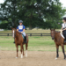 An instructor talking to two people on horseback.