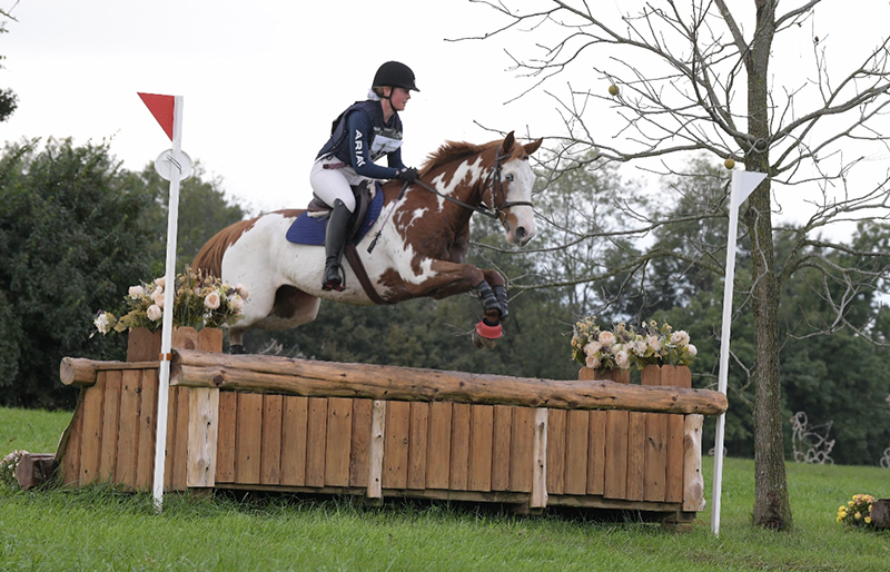 A young woman jumping her horse over a cross-country jump.