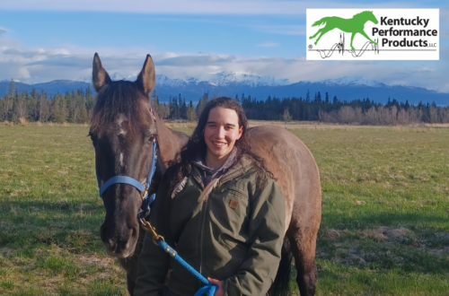 A young woman with her horse, smiling at the camera.