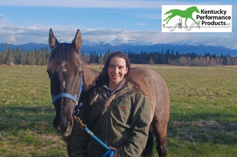 A young woman with her horse, smiling at the camera.