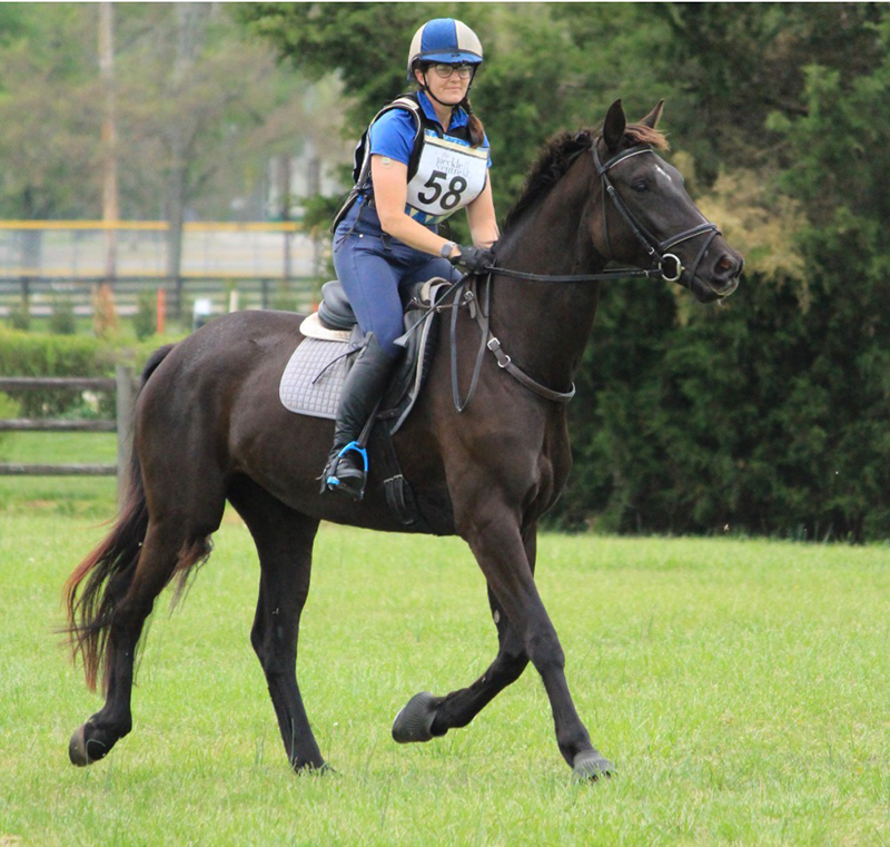 A woman riding her horse outside.