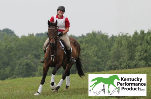A young woman riding a horse on a cross-country course, smiling.