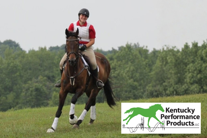 A young woman riding a horse on a cross-country course, smiling.